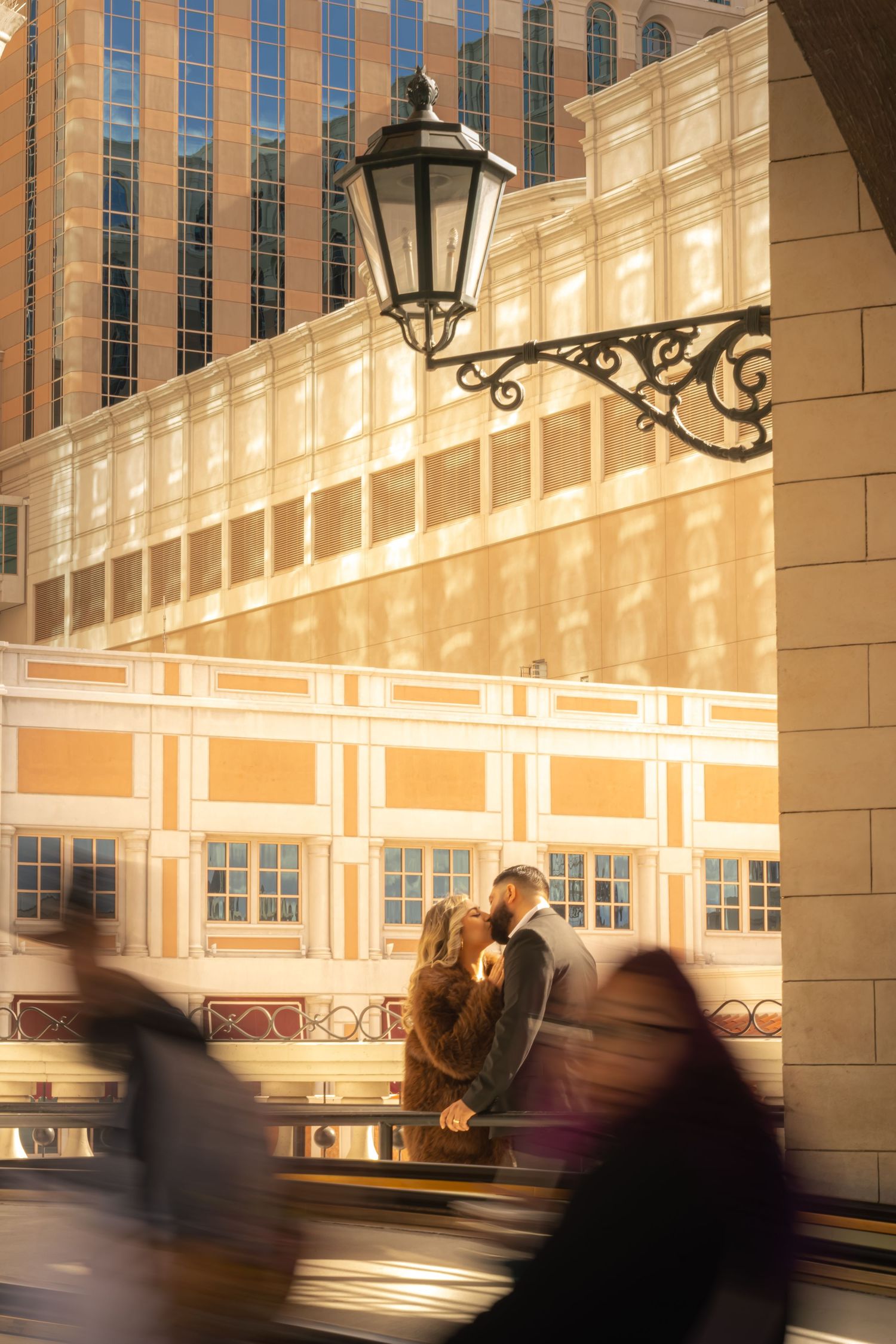 Couple kissing near a vintage street lamp at The Venetian Las Vegas amid motion-blurred crowd.
