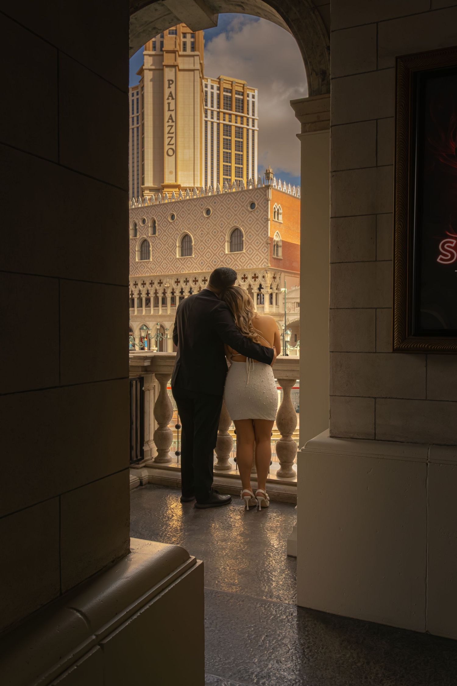 Newlyweds gazing at The Palazzo Las Vegas from a balcony archway in warm golden light.