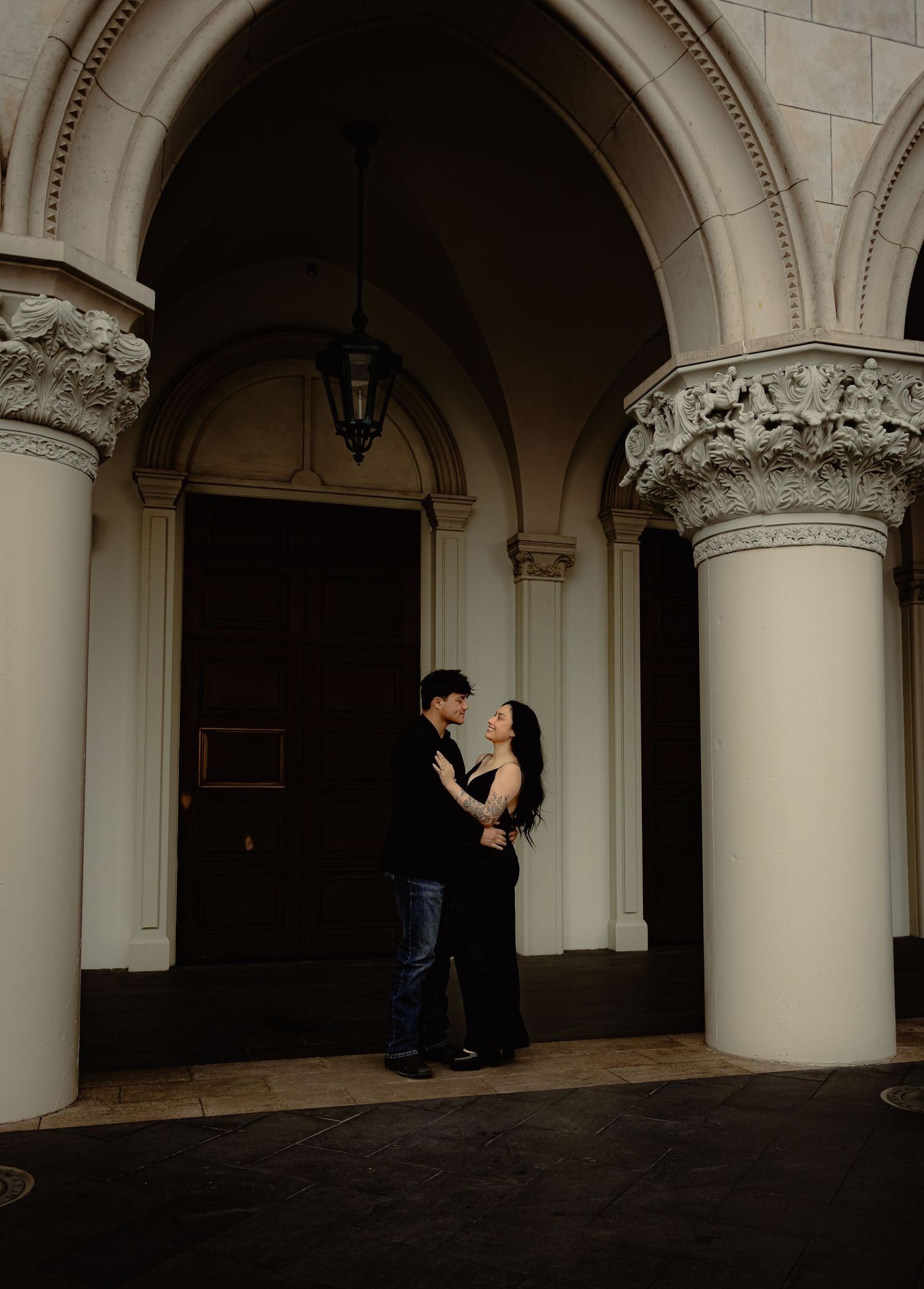 Couple in black attire sharing a romantic moment under ornate arched columns at The Venetian Las Vegas.