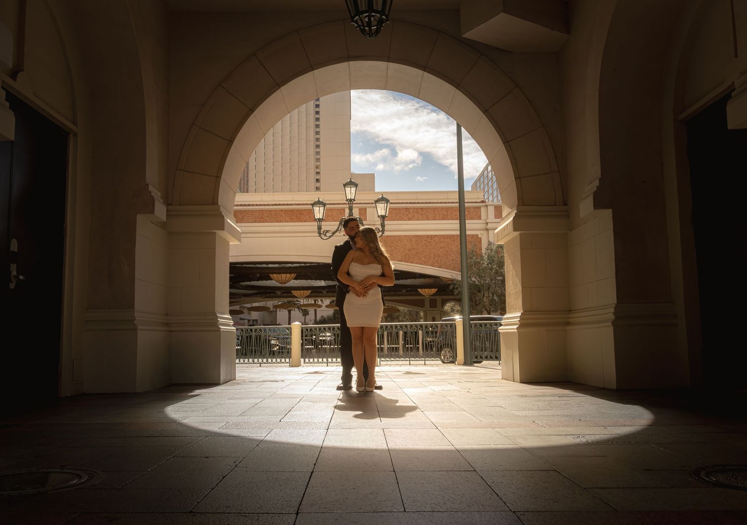 Couple silhouetted in dramatic spotlight beneath ornate arch at The Venetian Las Vegas resort.