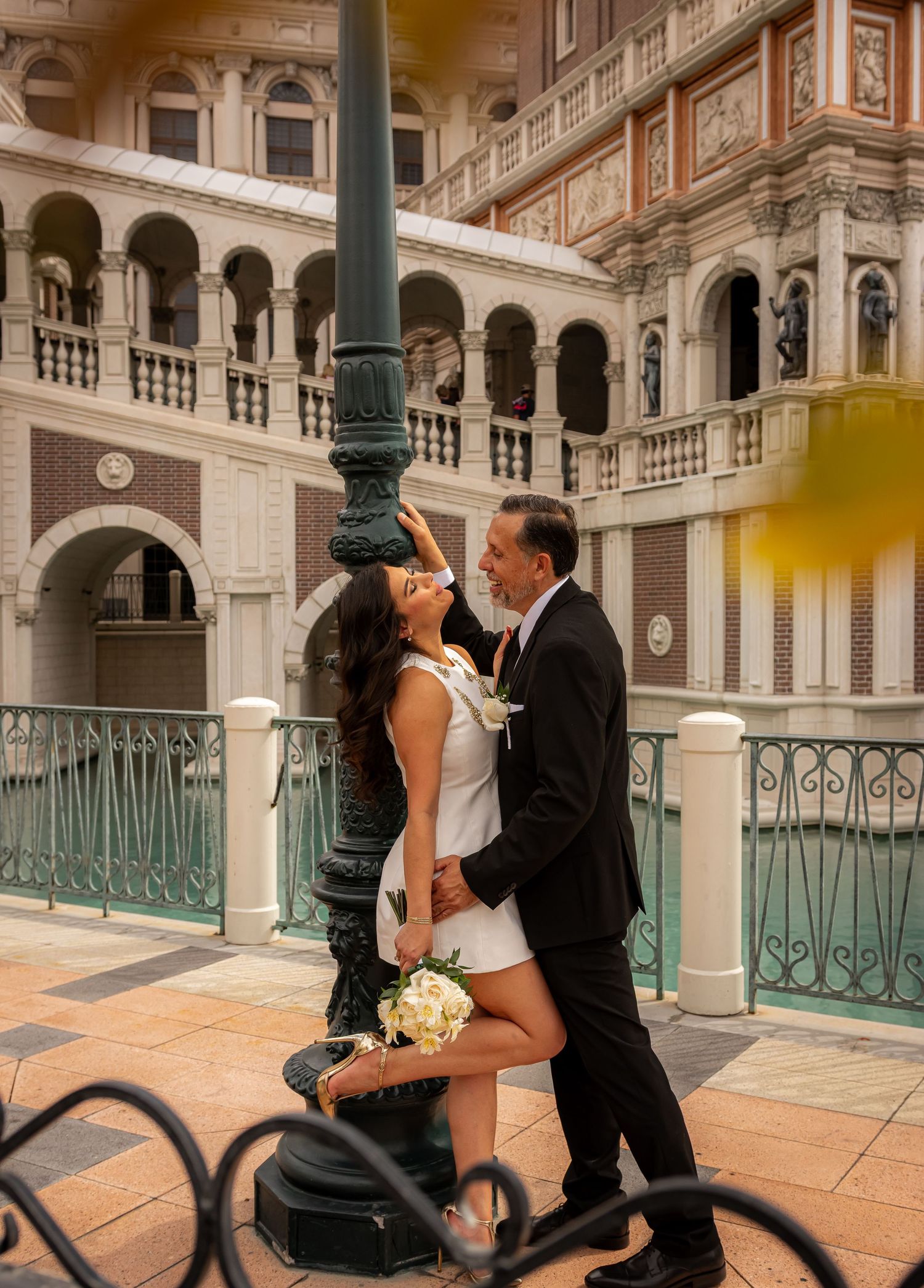 Newlyweds embracing by a lamppost with Venetian-inspired architecture at The Venetian Las Vegas resort.