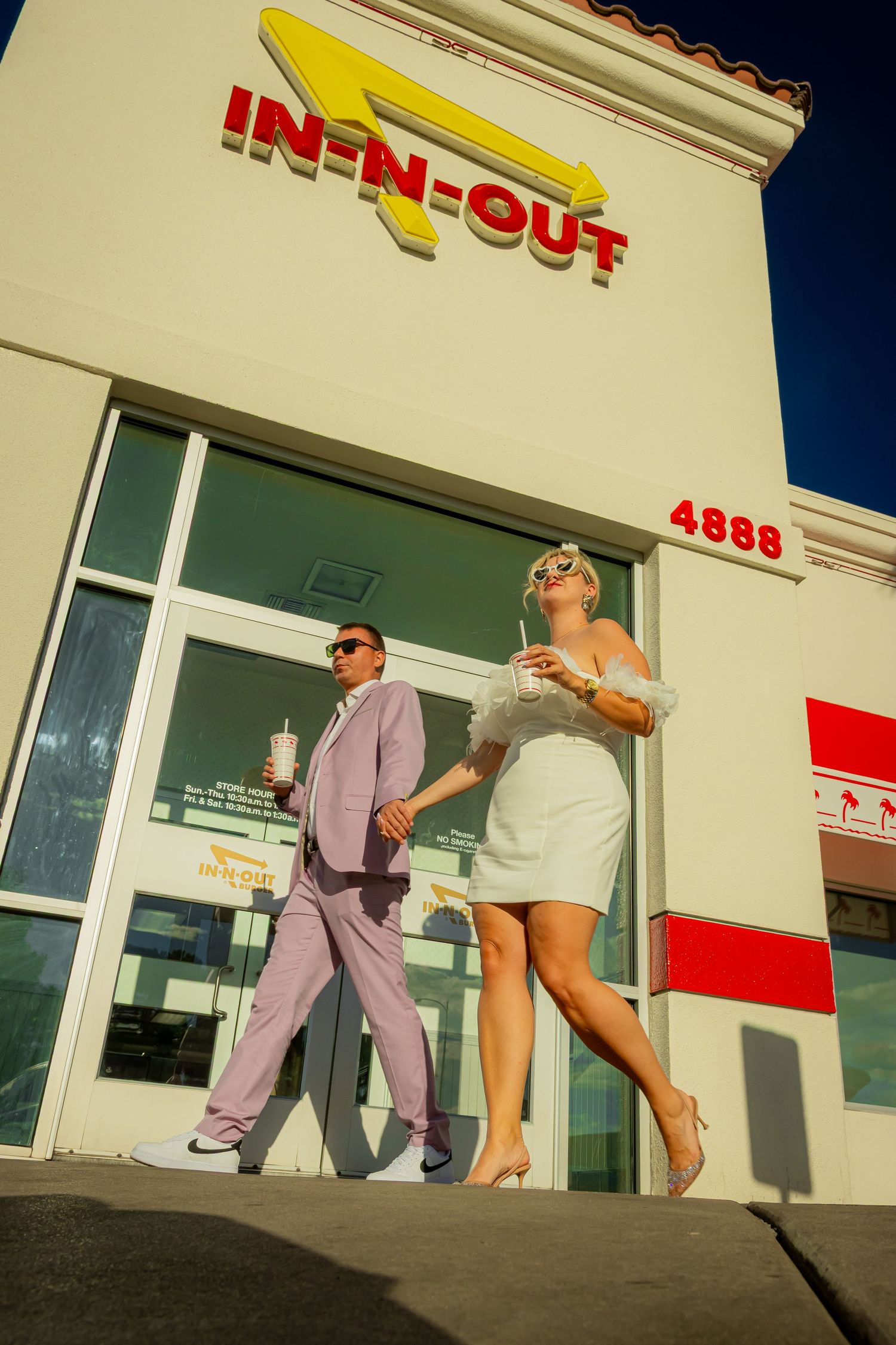 Newlyweds in wedding attire walking out of In-N-Out Burger on the Las Vegas Strip.
