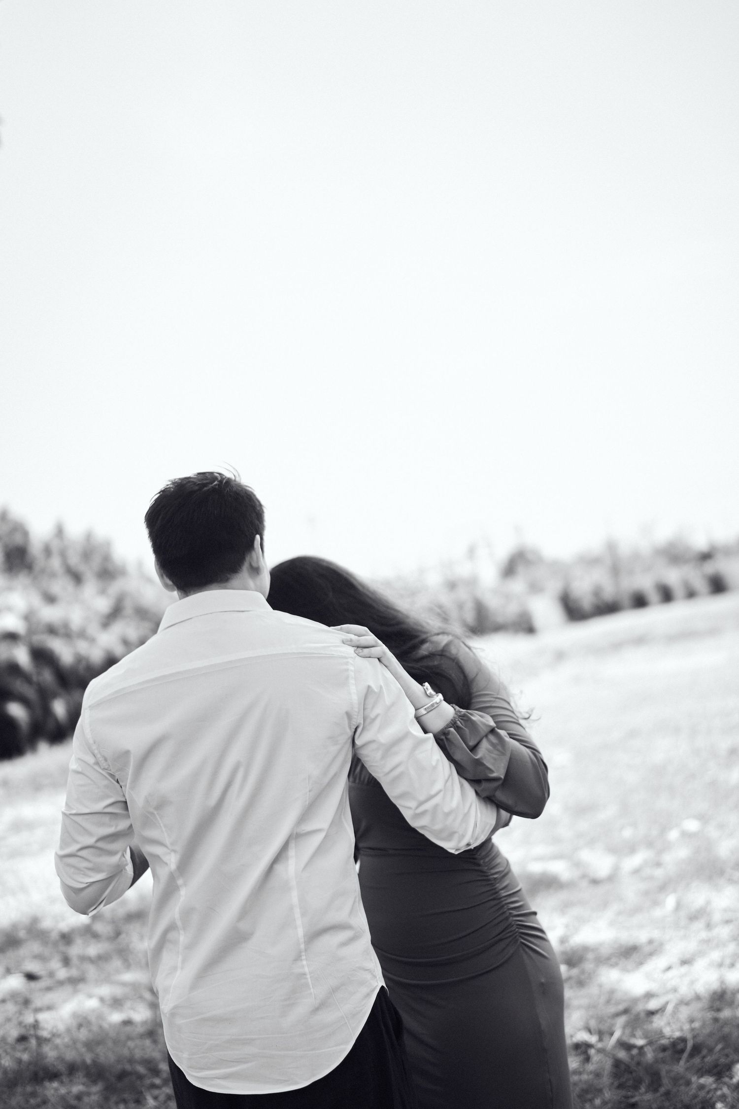 Romantic black and white photo of a couple walking together with the woman resting her head on the mans shoulder.