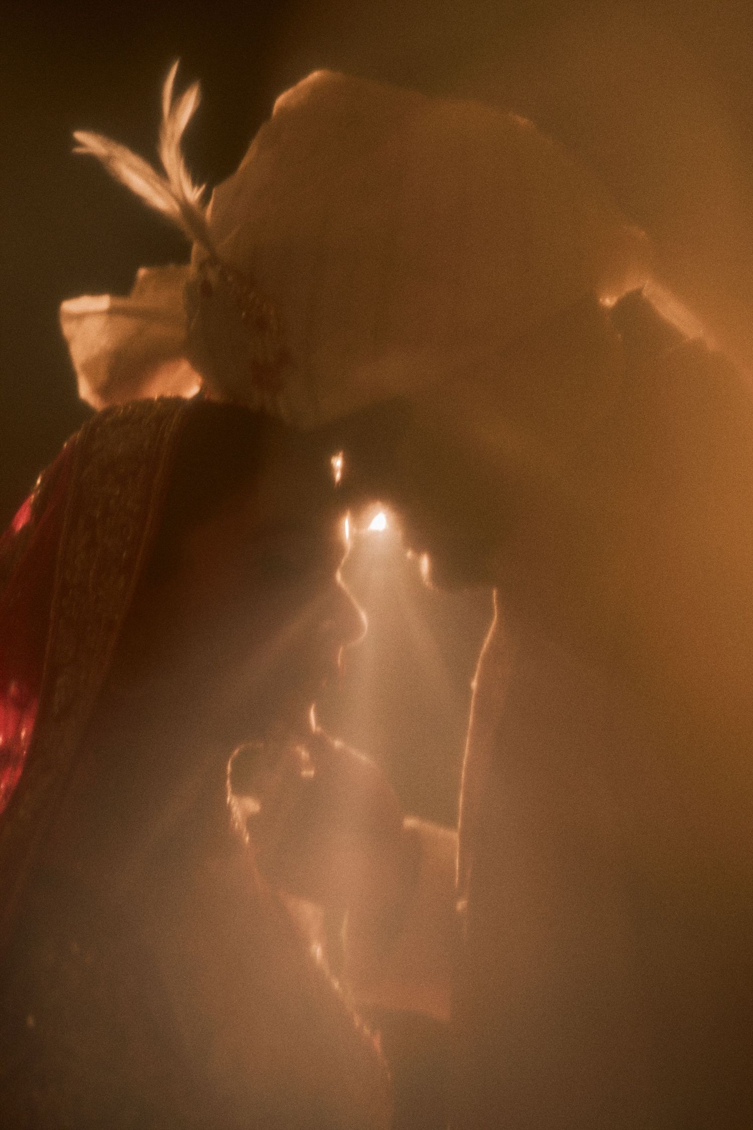 Dreamy silhouette of Indian groom in turban with bride in warm golden light during wedding.