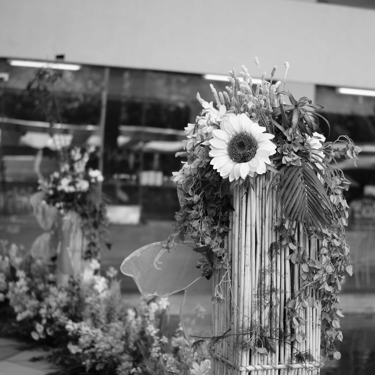 Elegant floral arrangement with sunflower on decorative birdcage at wedding venue, black and white.