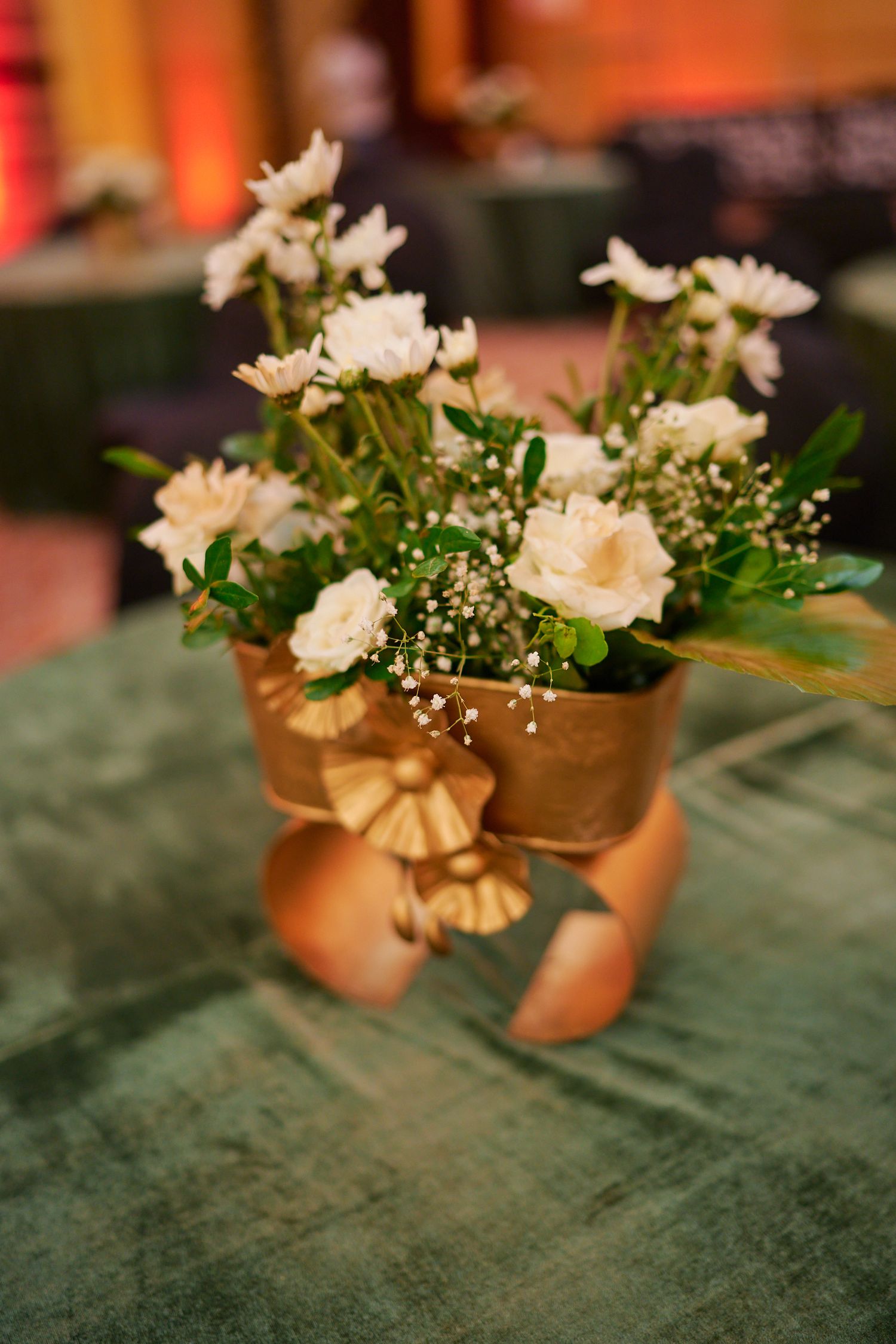 Gold pot with white roses, chrysanthemums, and baby's breath tied with satin ribbon bow.