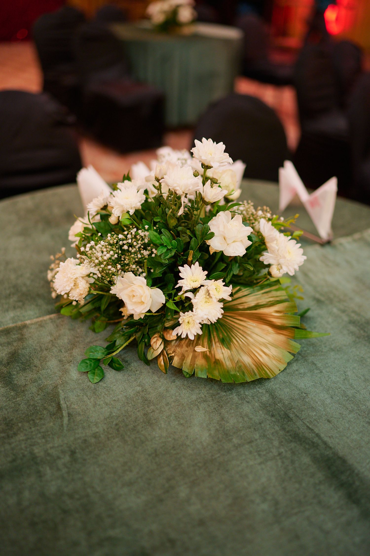 White roses and chrysanthemums bouquet with baby's breath on green velvet table centerpiece.