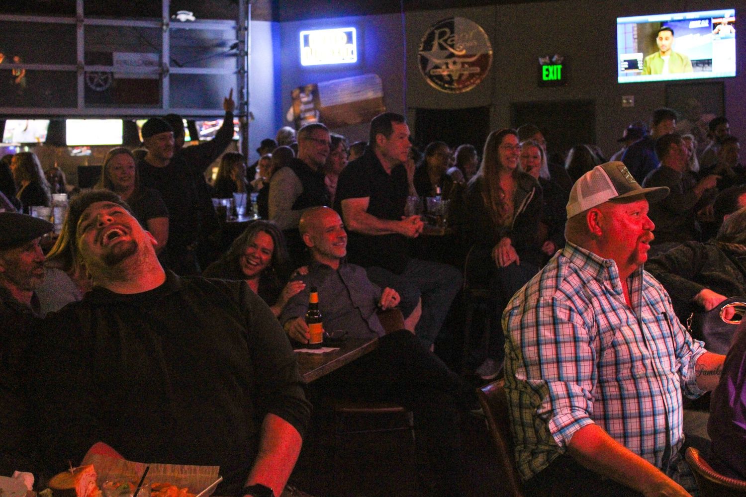 Crowd of people watching a live piano bar event at a bar.
