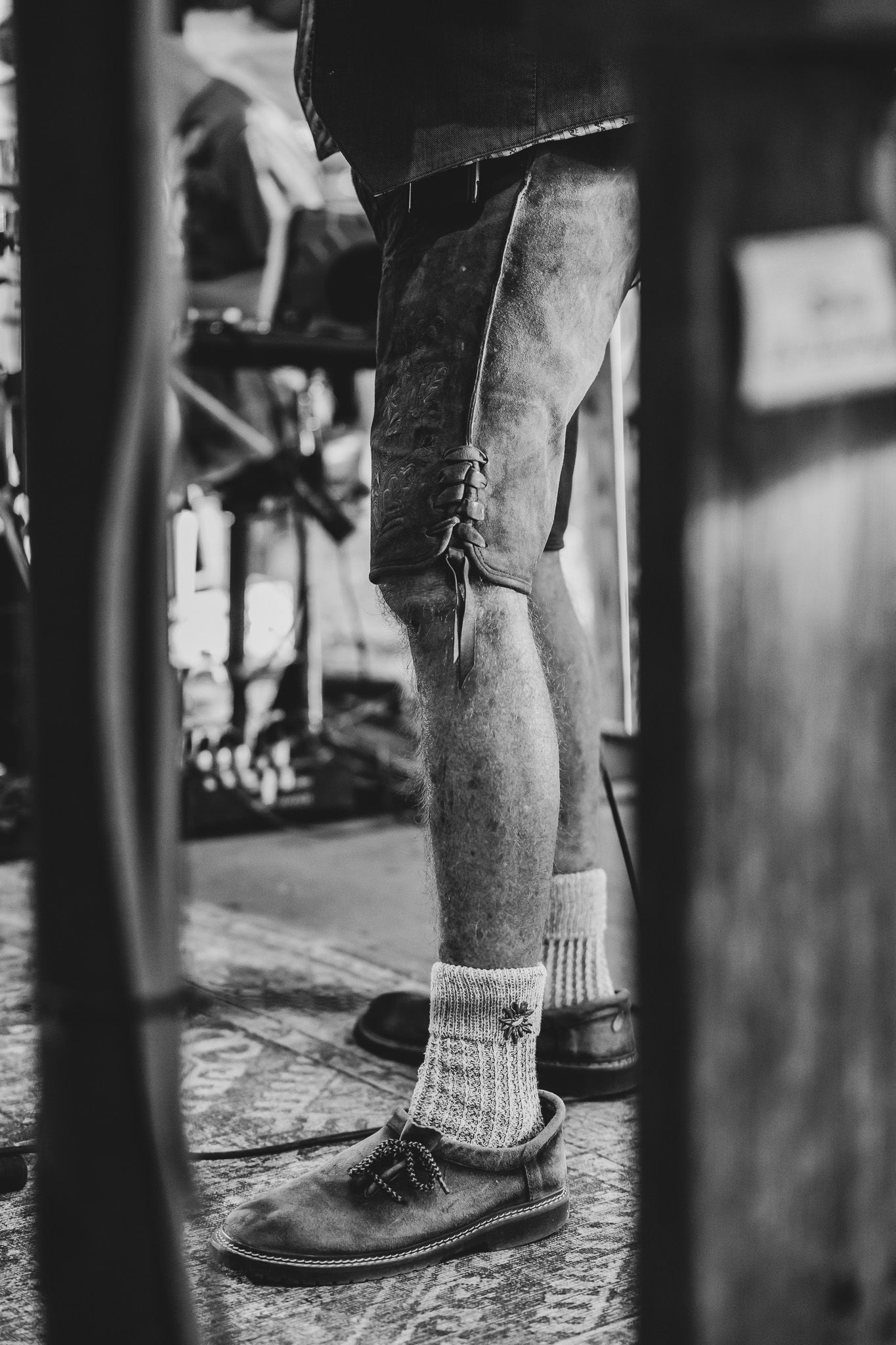 Black and white close-up of a performer wearing traditional German lederhosen, wool socks, and suede slippers on stage.
