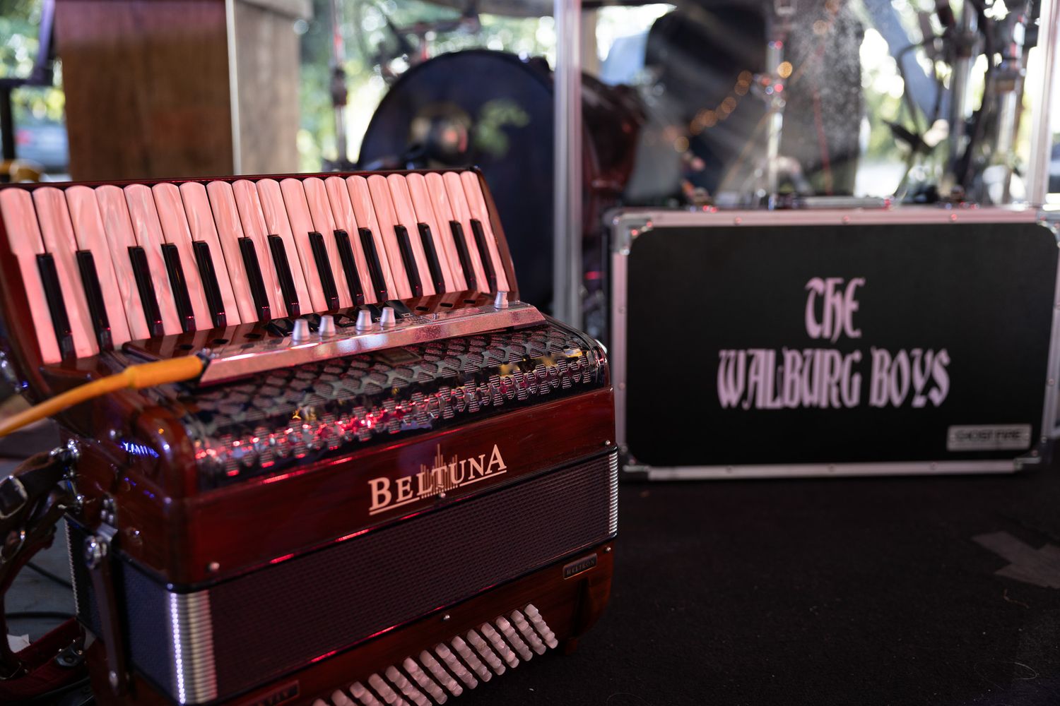 Red Beltuna accordion displayed beside The Walburg Boys band equipment case.