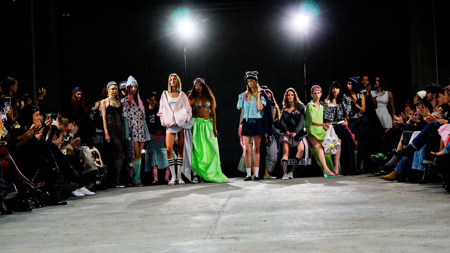 Group of models take a bow together at the end of an indoor fashion show.