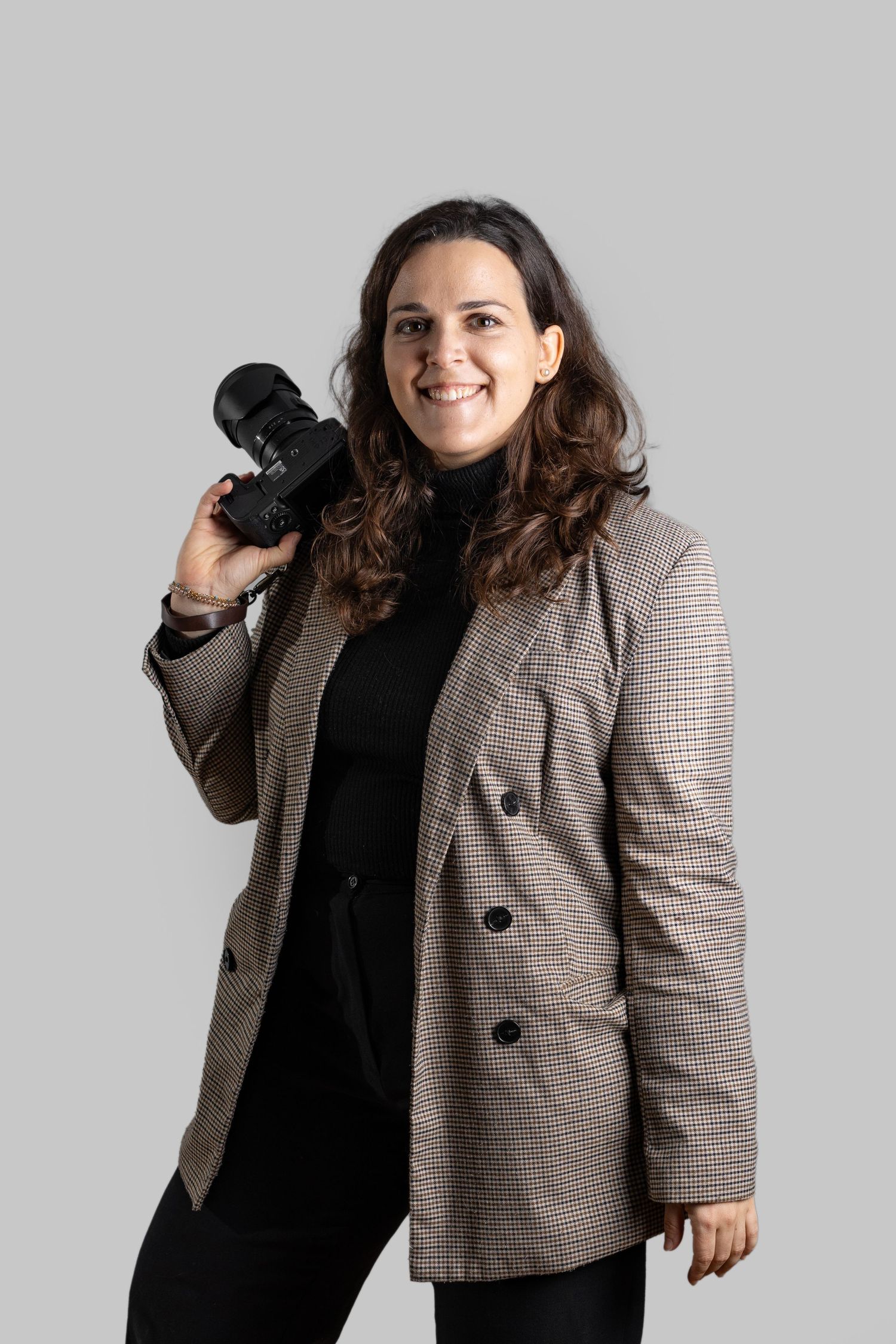 Professional photographer wearing plaid blazer and black top poses with camera against white background in three poses.