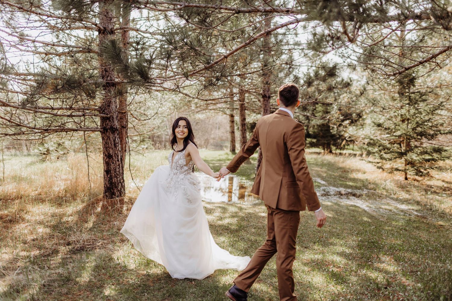 bride and groom waking past each other while trying to not let go of each others hands,