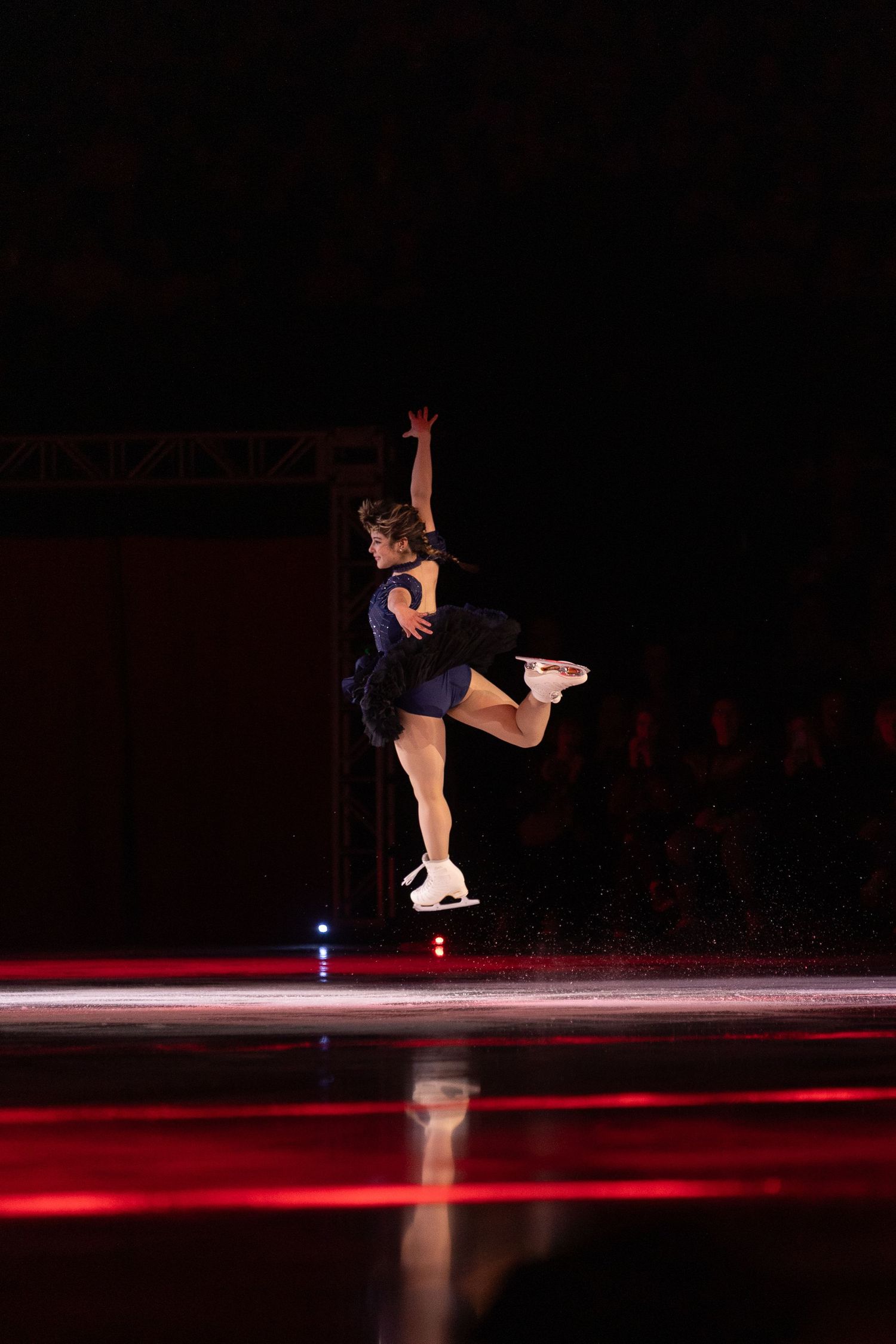 alysa liu, figure skater, doing a little leap with one foot popped back and one arm up during her stateside program.