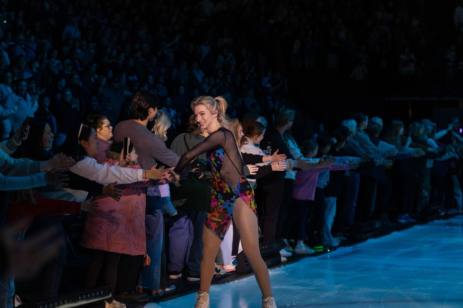 Amber Glenn, figure skater, meeting spectators on the side of the ice and giving high fives.