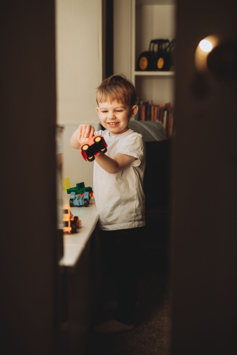 A boy playing with cars, documentary-style family photography capturing everyday life