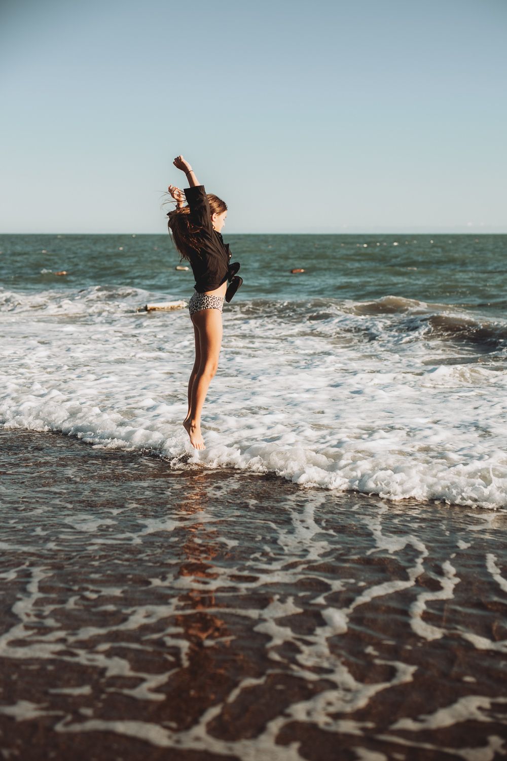 A child  jumping in the sea during an outdoor family photoshoot