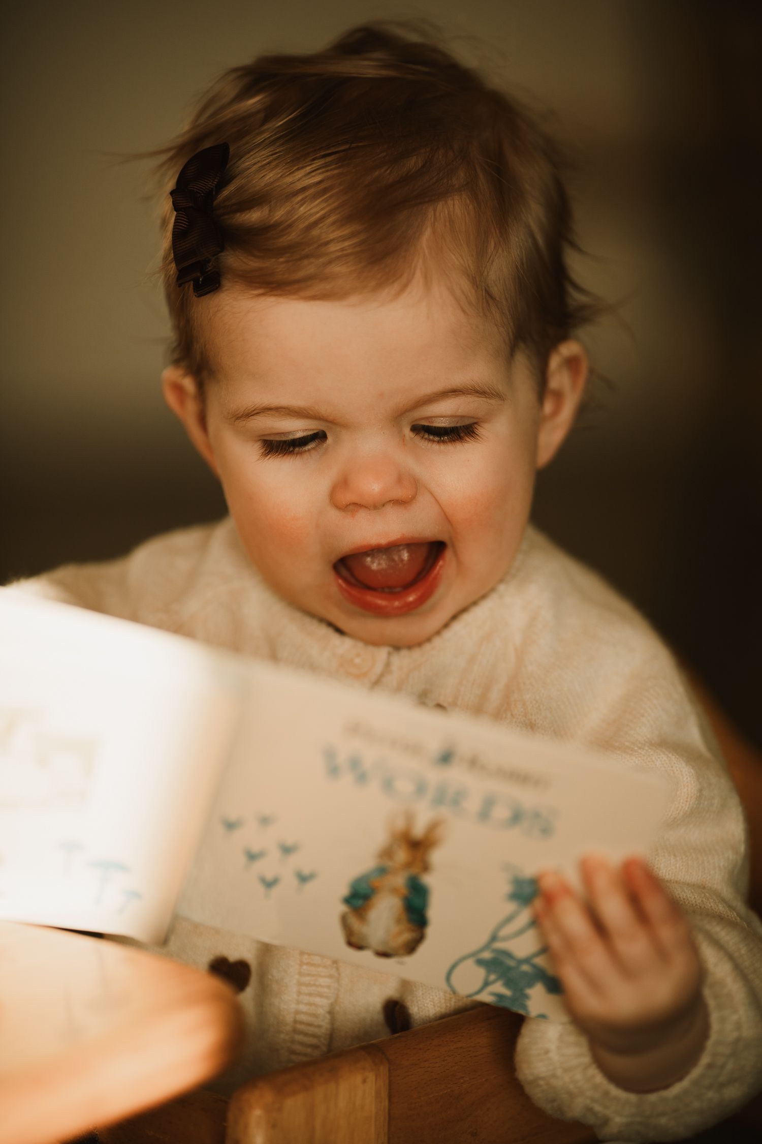 Relaxed family photoshoot with toddler and parents indoors, a portrait of a toddler looking through a book