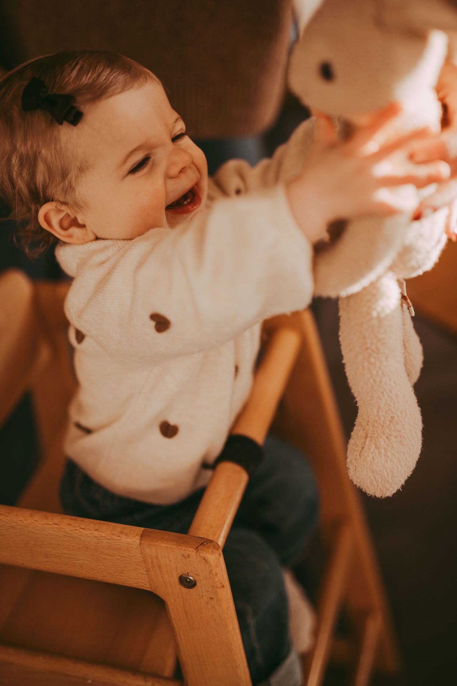 A toddler captured reaching out for a toy during a family photoshoot indoors