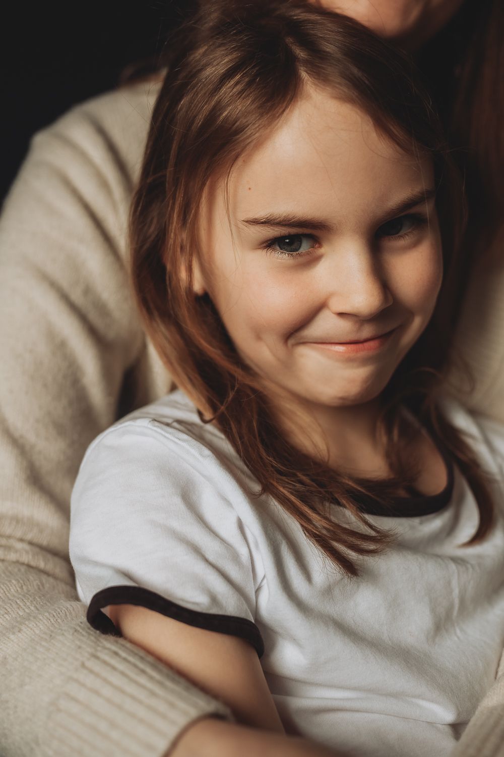 A portrait of a girl smiling in her mothers arms,  lifestyle family photography indoors