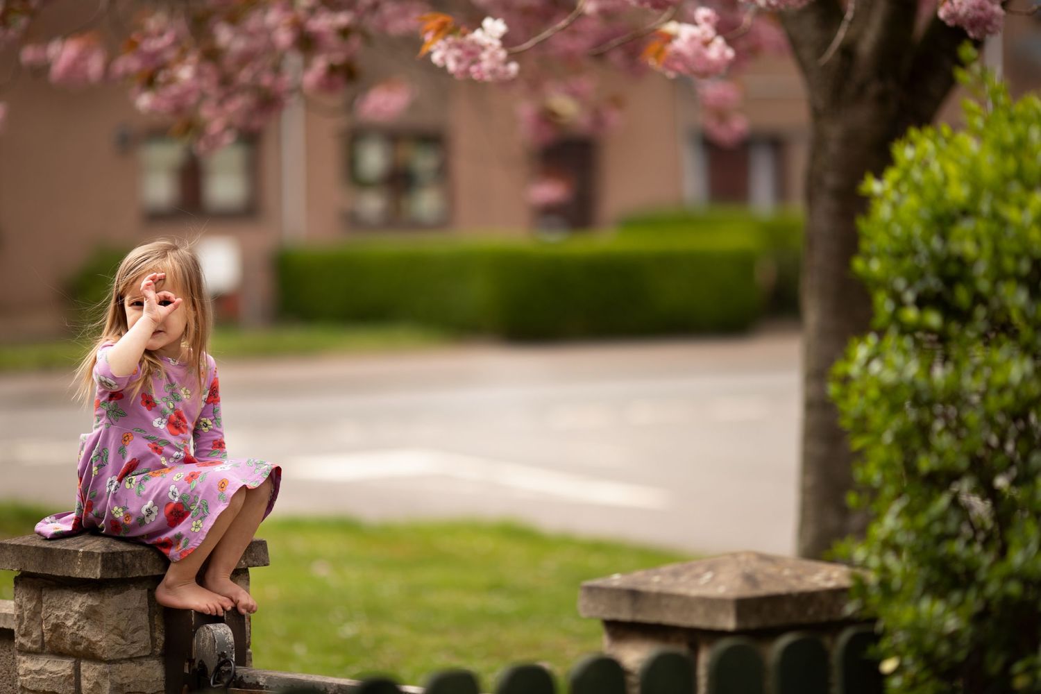 Young girl sitting  under blossoming tree outdoors, natural family portrait.