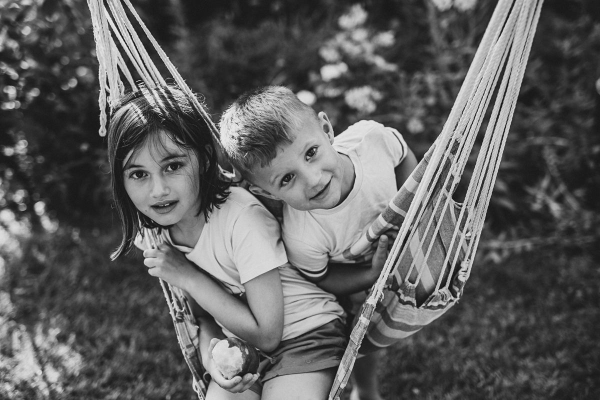 Children swinging on a hammock during natural family photography session outdoors