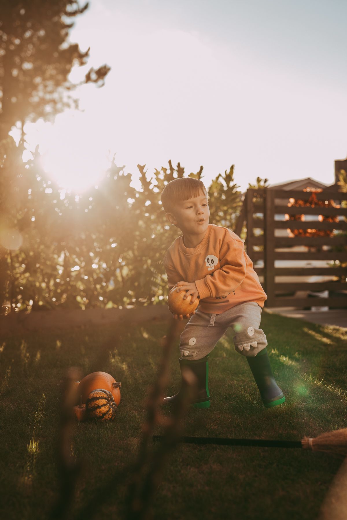 Outdoor family photography with a child playing in the garden with pumpkins, Halloween family photography.