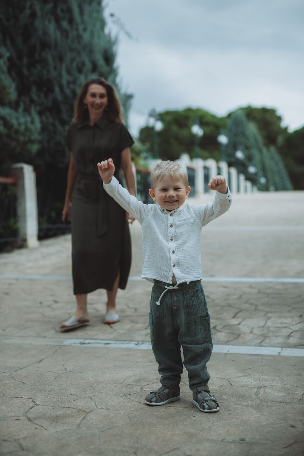 Child smiling looking at the camera during a family walk, mother in in the background,  lifestyle family photography
