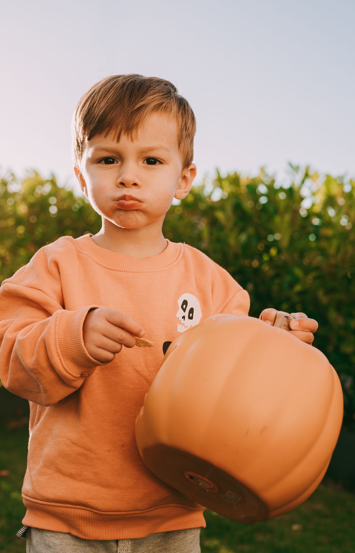 Outdoor family photography with a child playing in the garden with pumpkins, Halloween family photography.