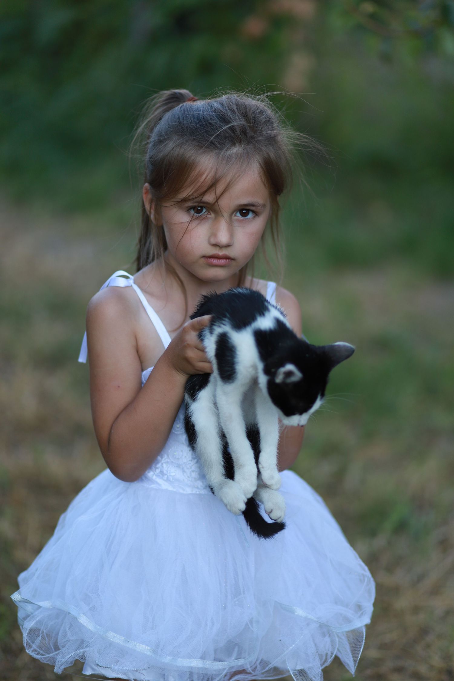 A girl holding a cat during a family photoshoot outdoors