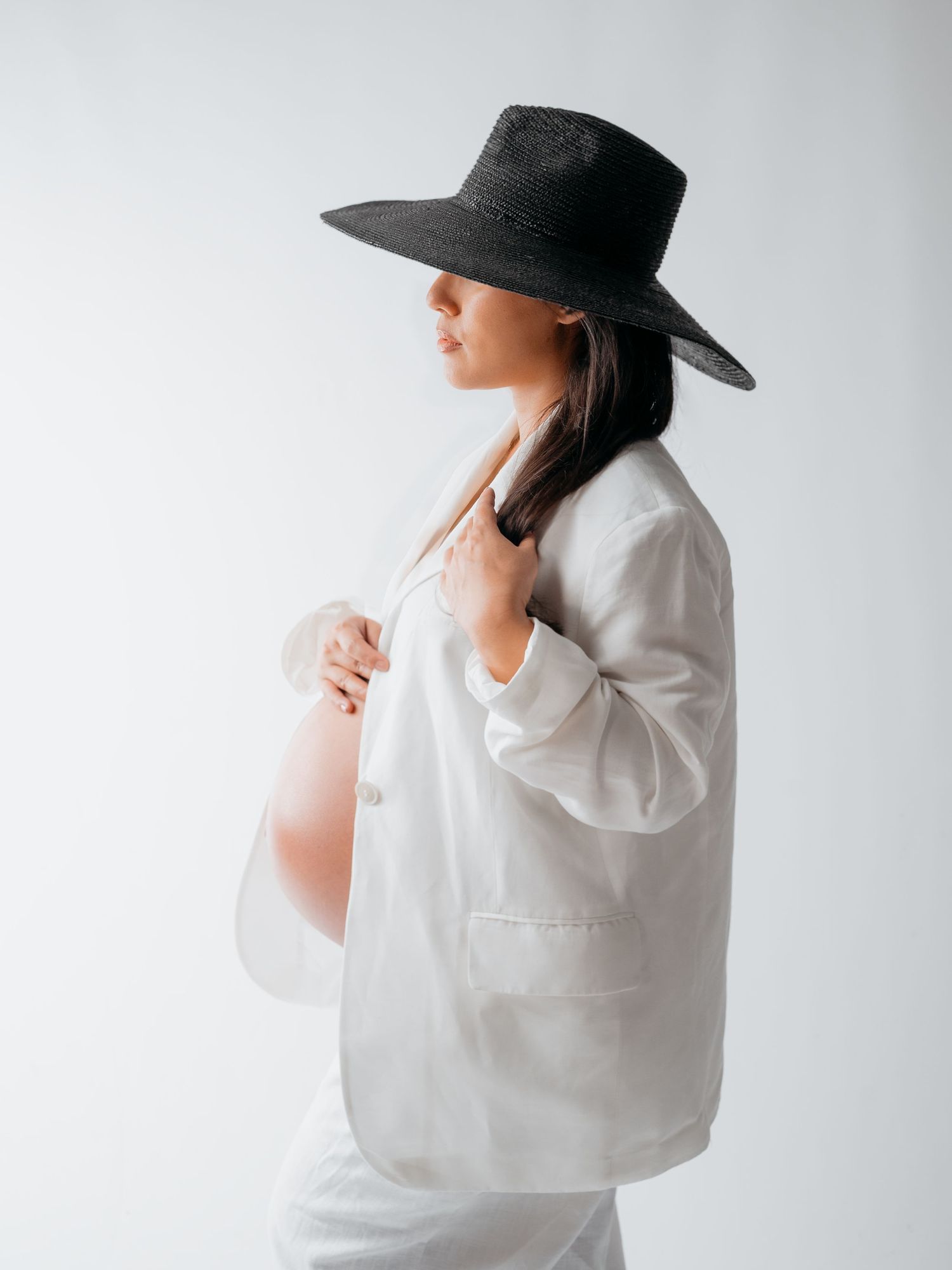 Schwangere Frau mit Hut im Studio – ruhige Babybauchfotografie in Nürnberg