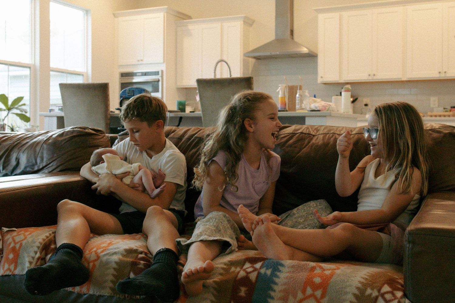 A group of people laughing and enjoying themselves while sitting on a couch together in a living room.