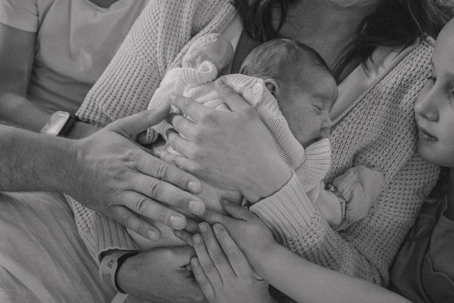 A series of black and white photographs showing hands holding and caressing a small baby.