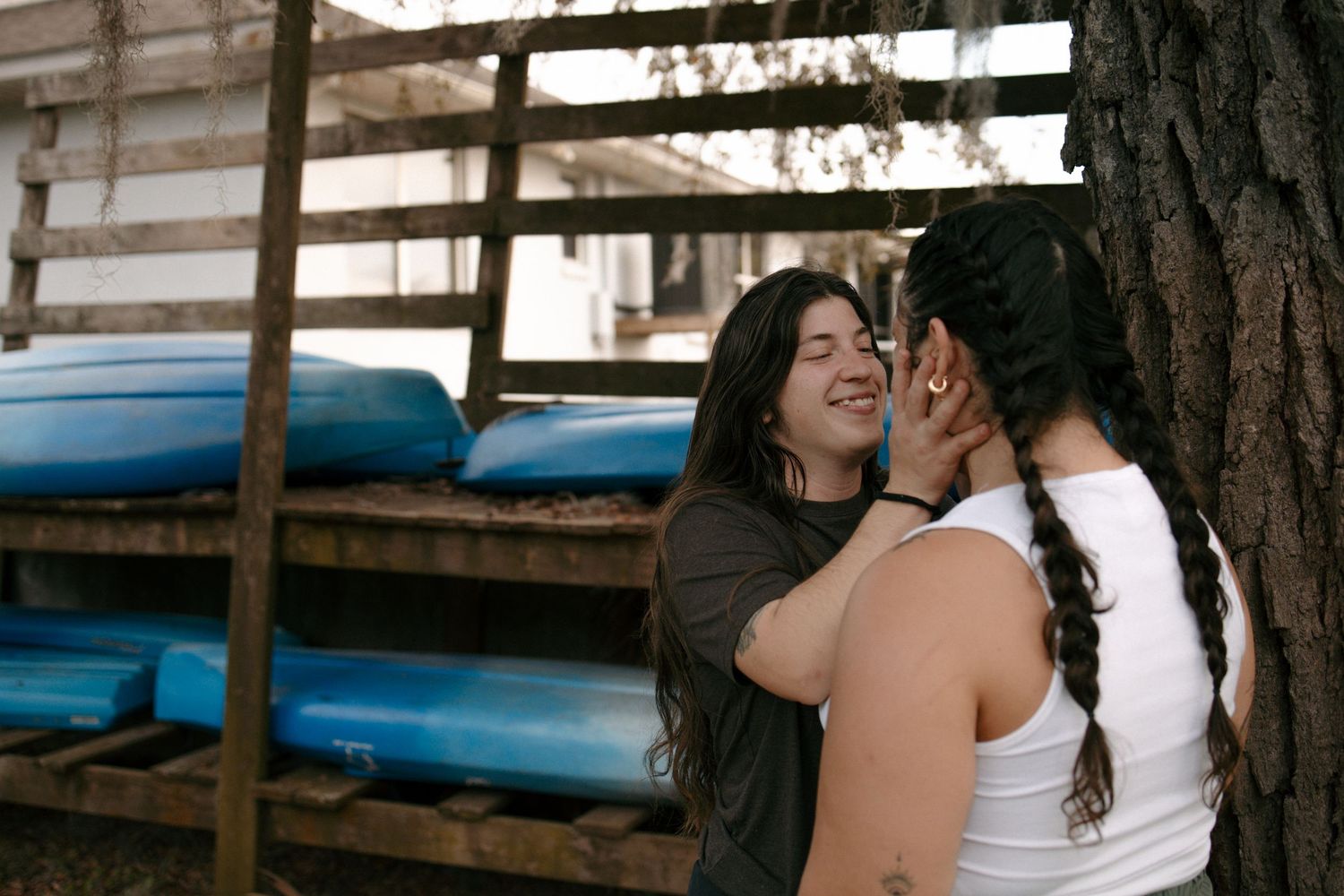 Friends sharing a moment outdoors near wooden structures and trees.