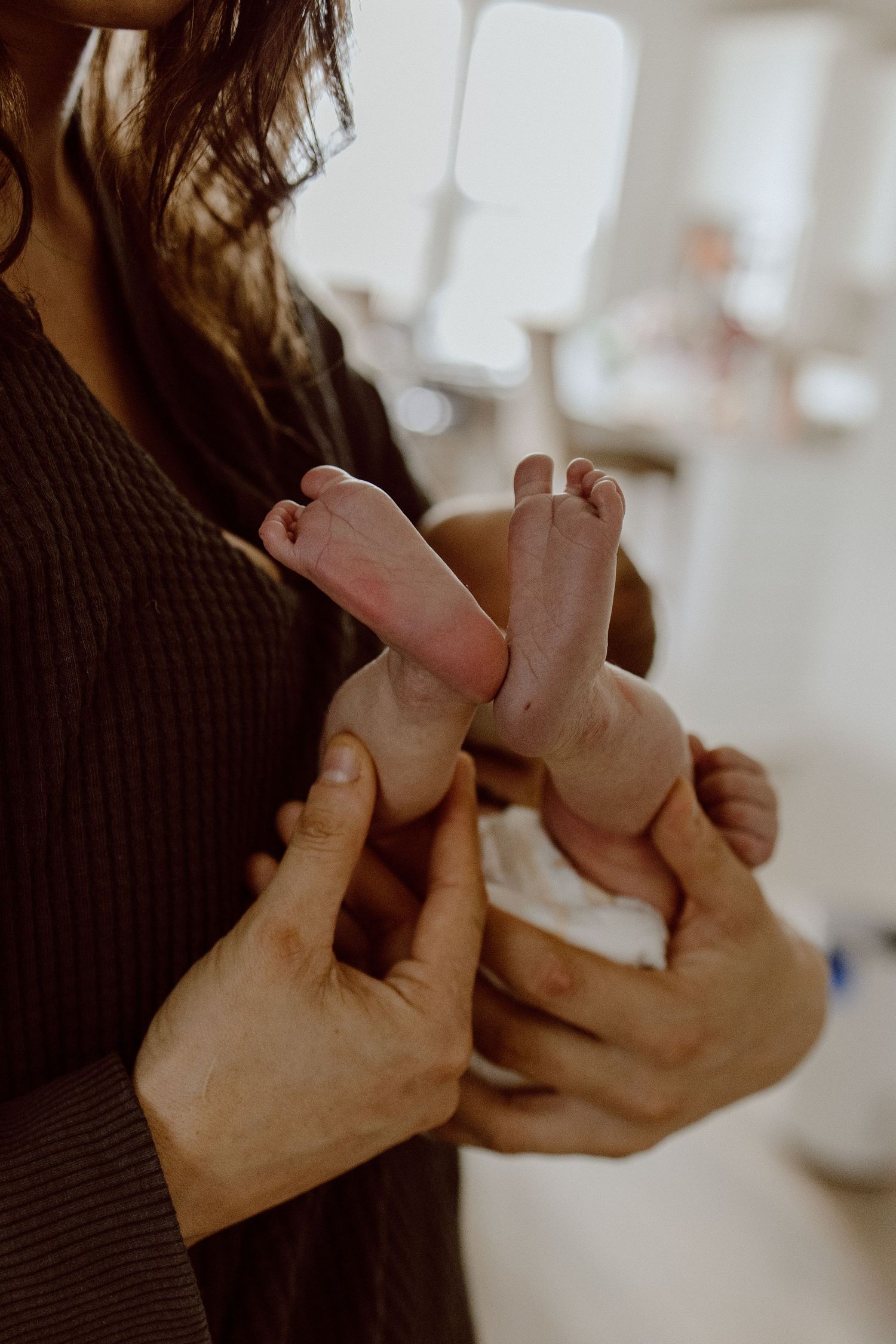 Close-up shot of tiny baby feet being gently held in adult hands against a blurred background.