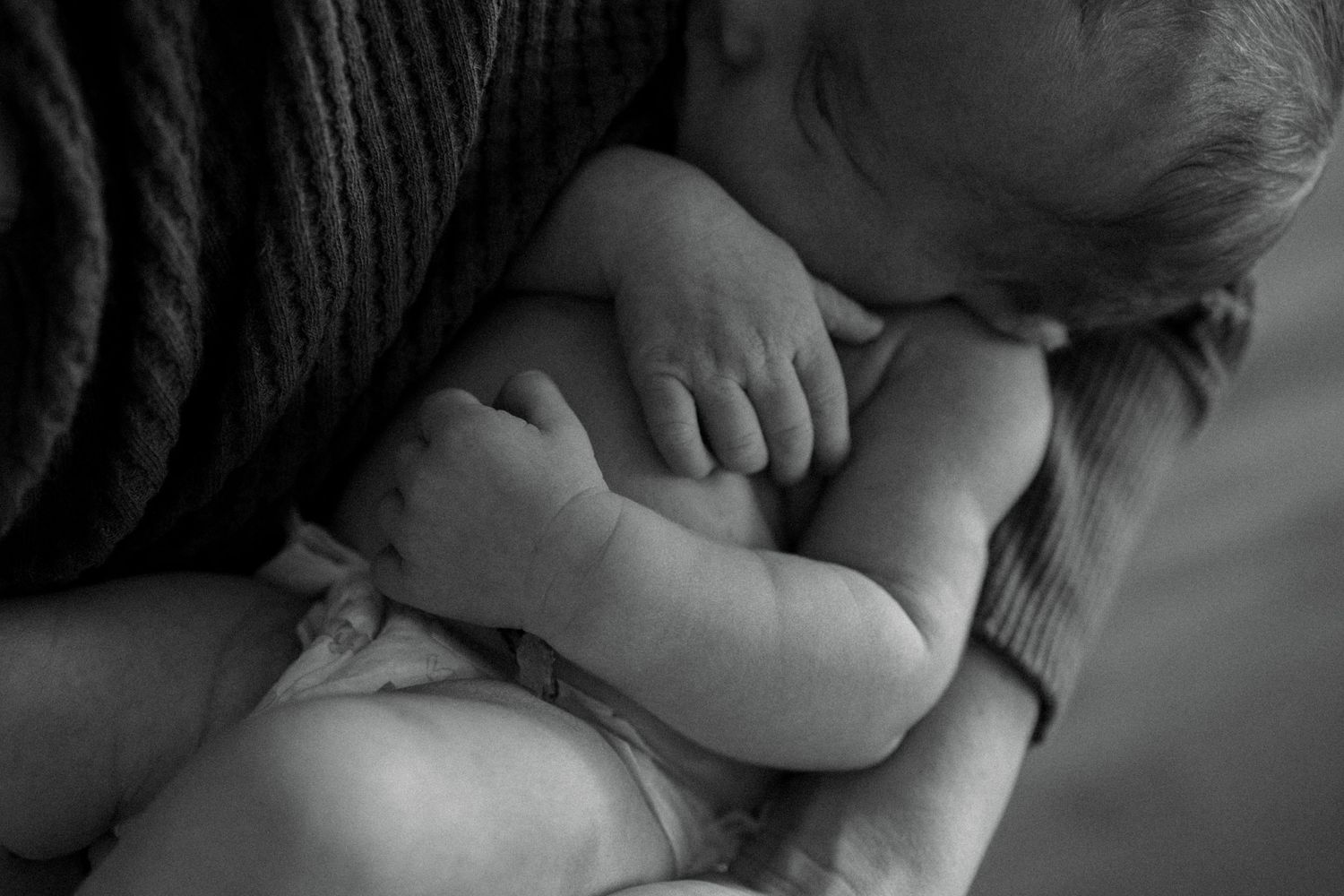 A black and white collage of tender moments between a parent and baby showing nurturing physical contact.
