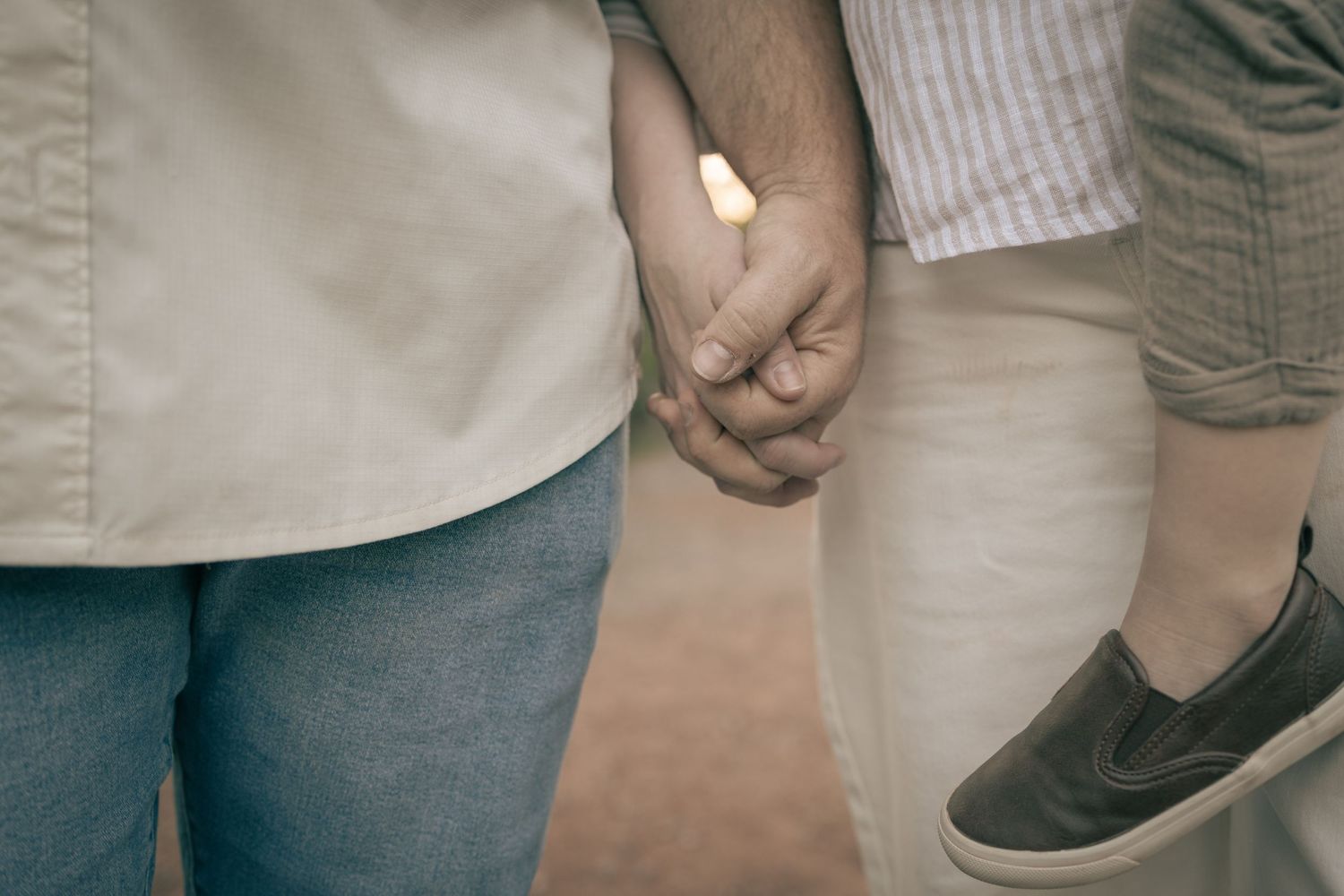 Close-up of a couple holding hands tenderly, wearing casual outfits, symbolizing love and connection.