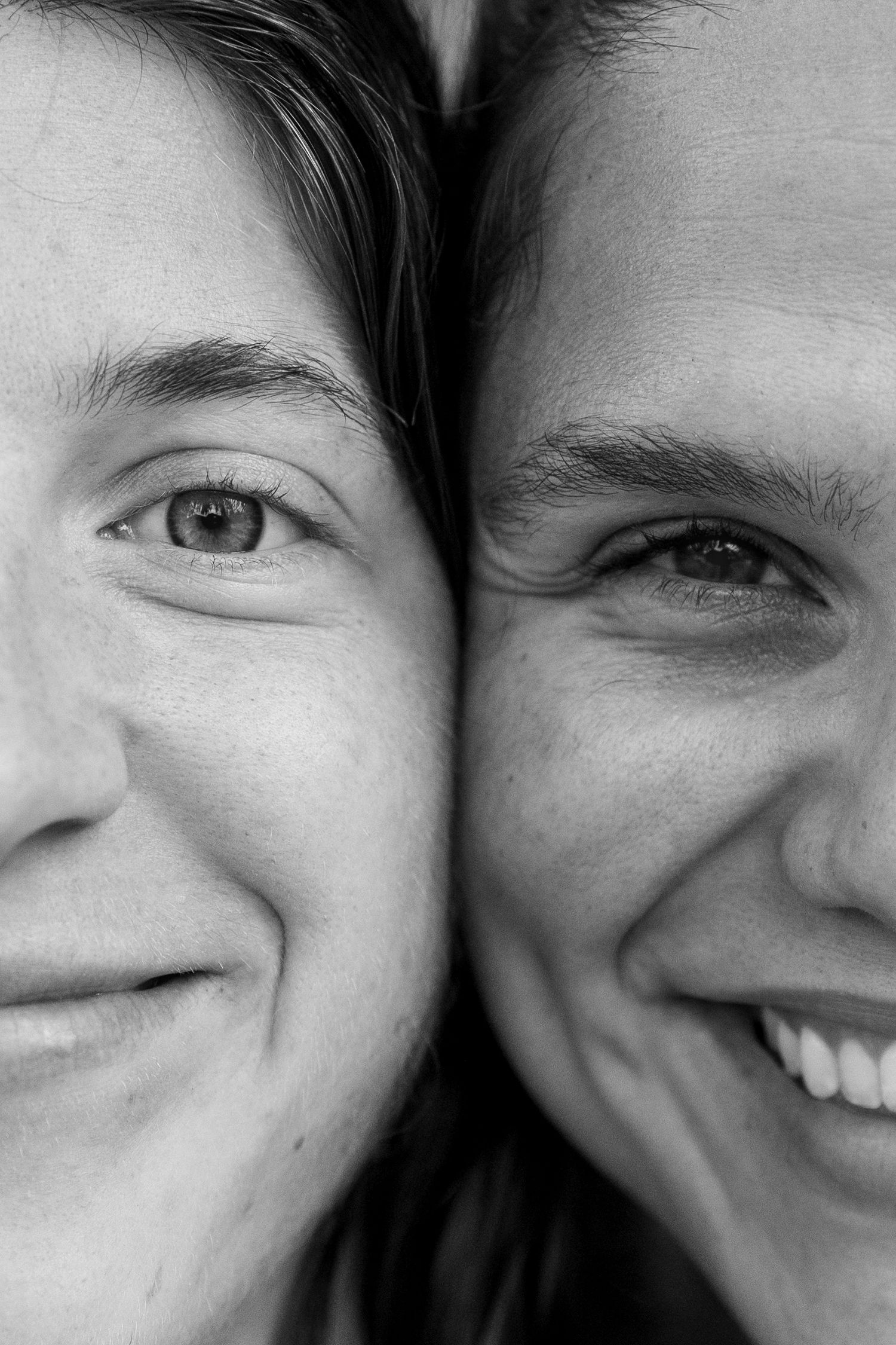 Close up black and white portrait of two smiling faces side by side.