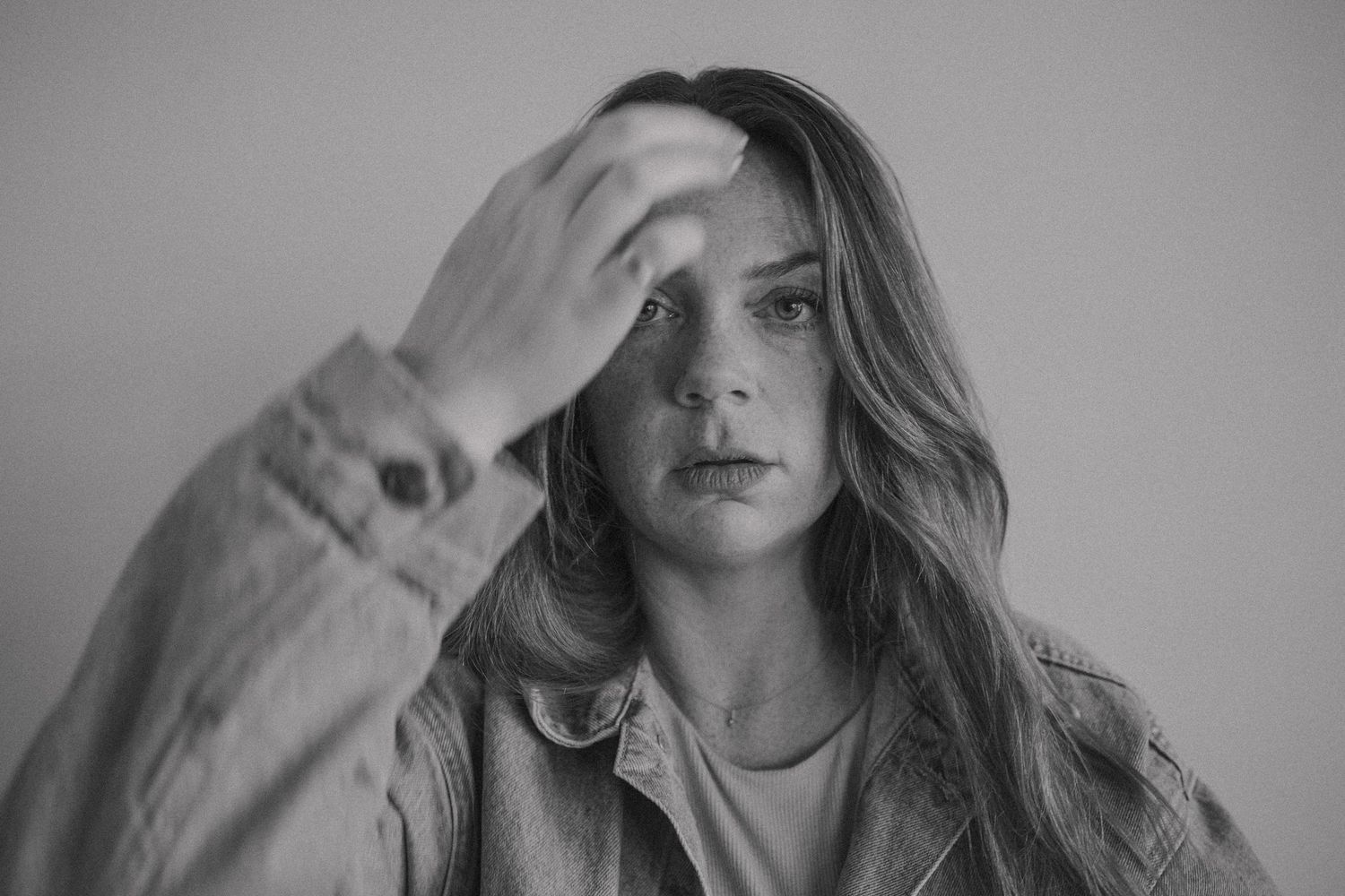 A series of black and white portraits showing a person with long hair in various expressive poses.