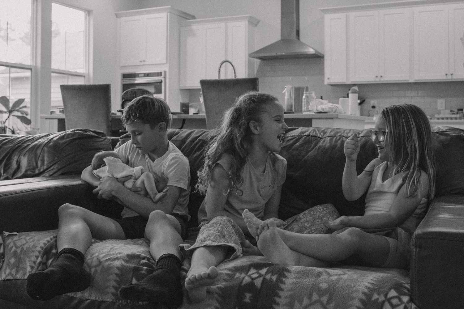A group of people relaxing on a couch in a living room while watching television together.