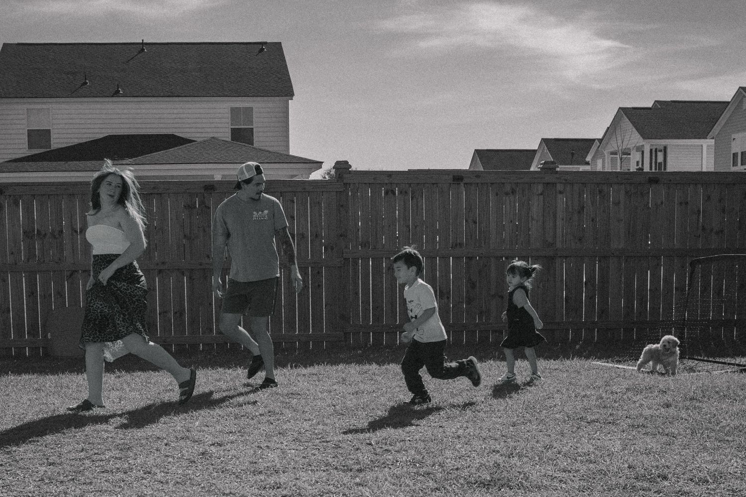 timeless candid photo. Family lifestyle income shoot. siblings hugging. Family dog. Family playing outside