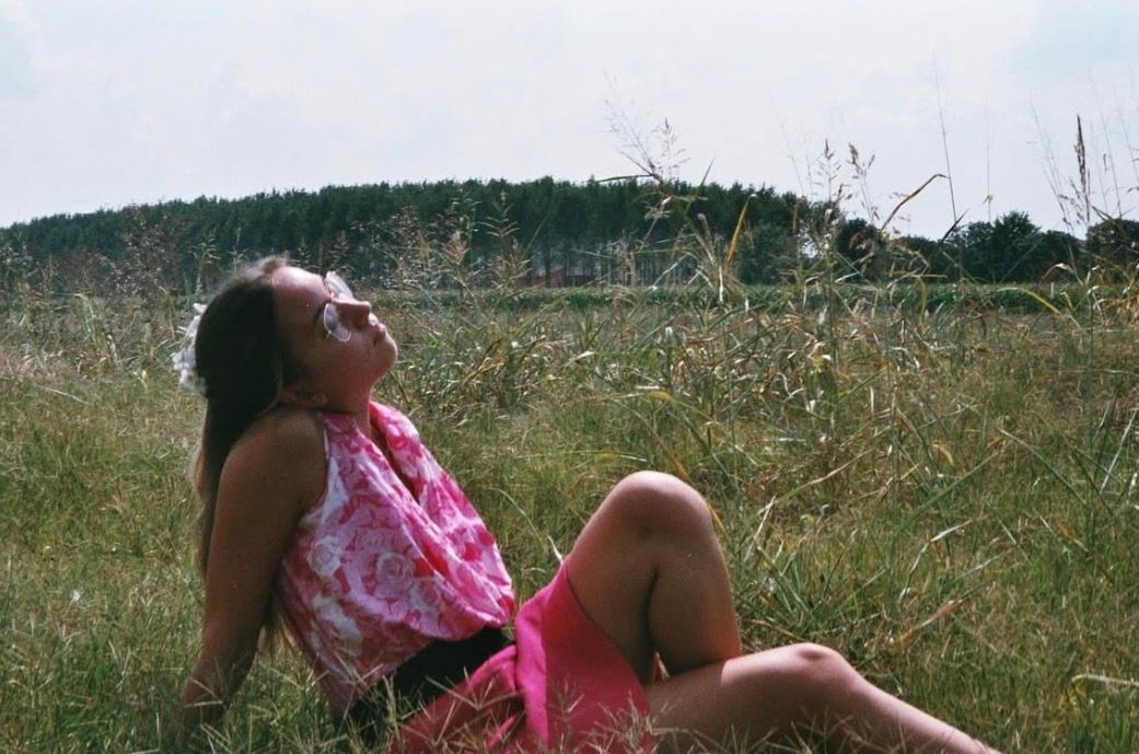 ritratto fotografia analogica ragazza con vestito rosa su prato
