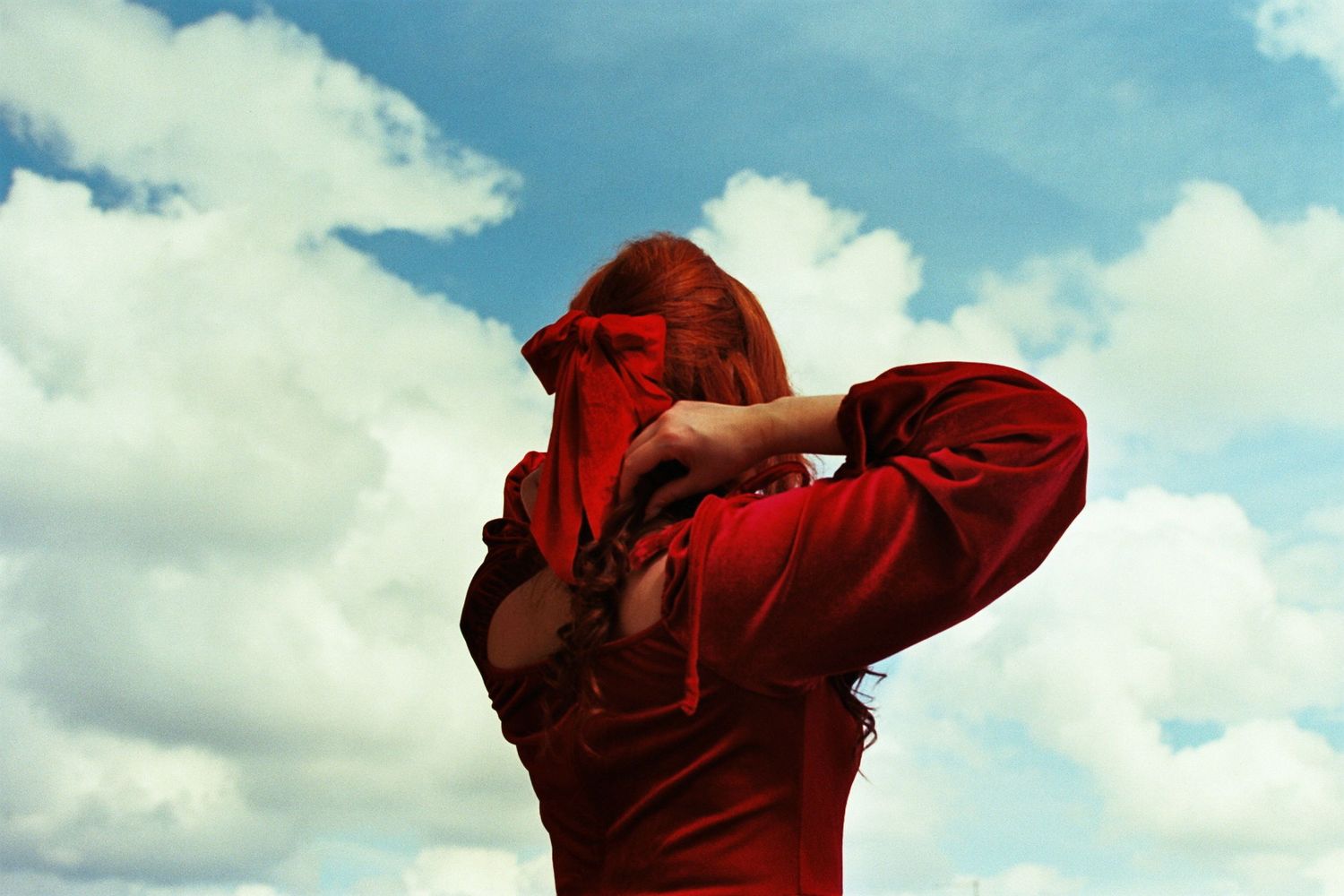 ritratto fotografia analogica ragazza con vestito rosso cielo con nuvole