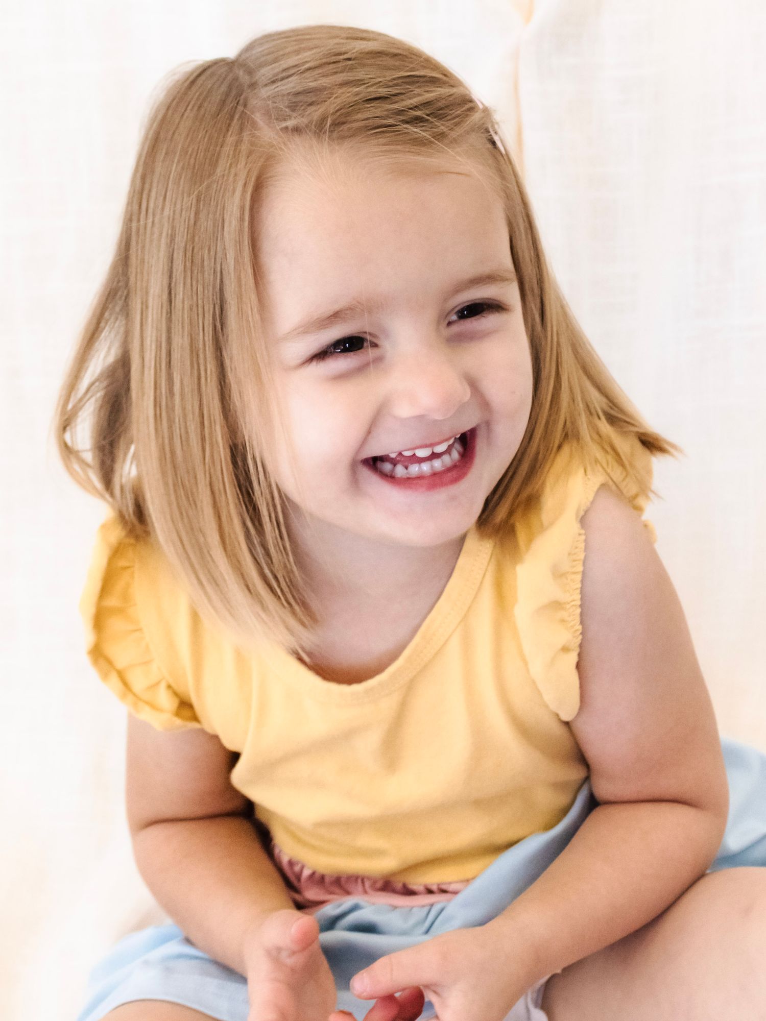 happy, natural, candid children's studio photography. Happy child posing in front of a white backdrop. Children's milestone photography