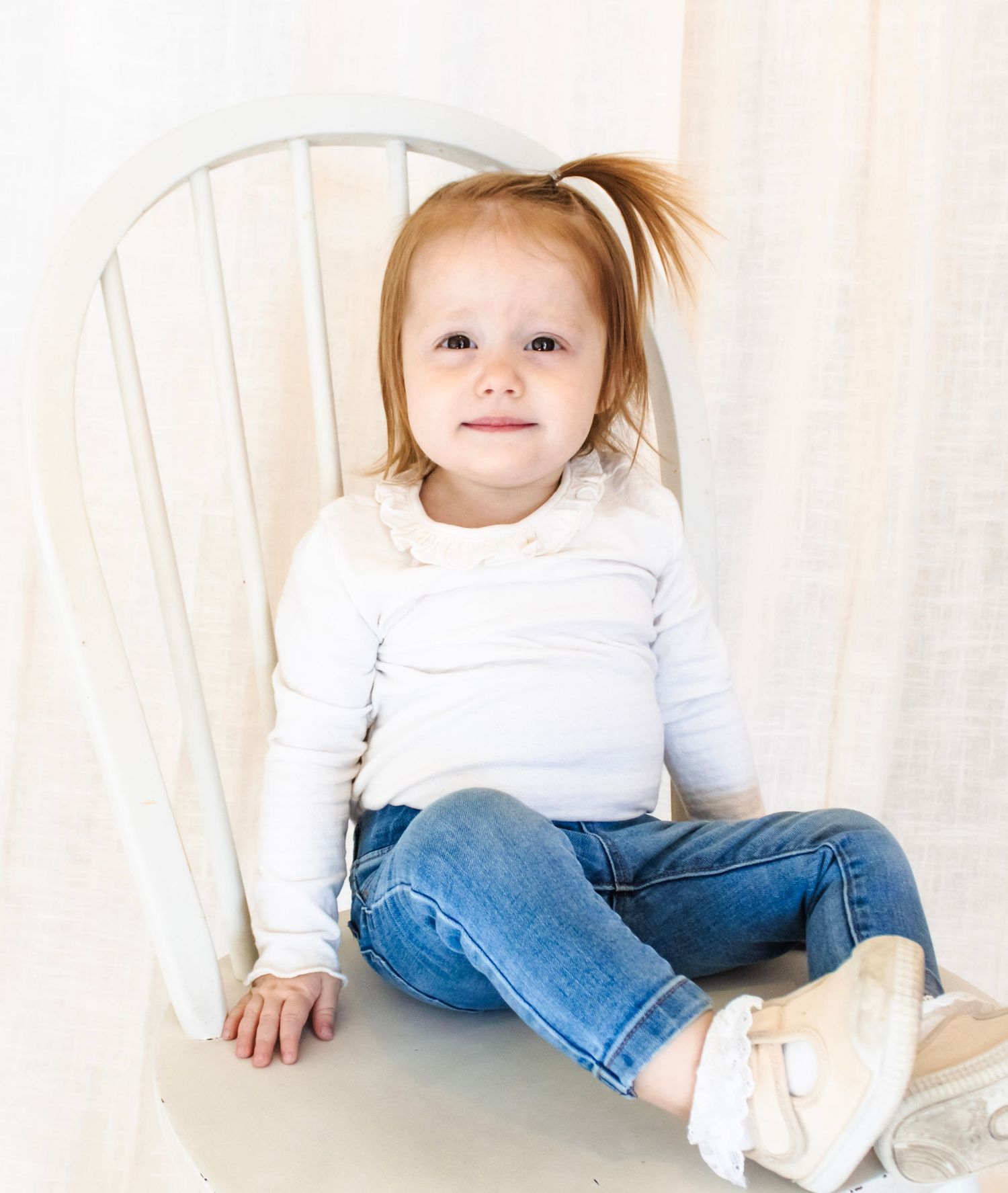 candid children's studio photography. Happy child posing in front of a white backdrop. Children's milestone photography in florence arizona
