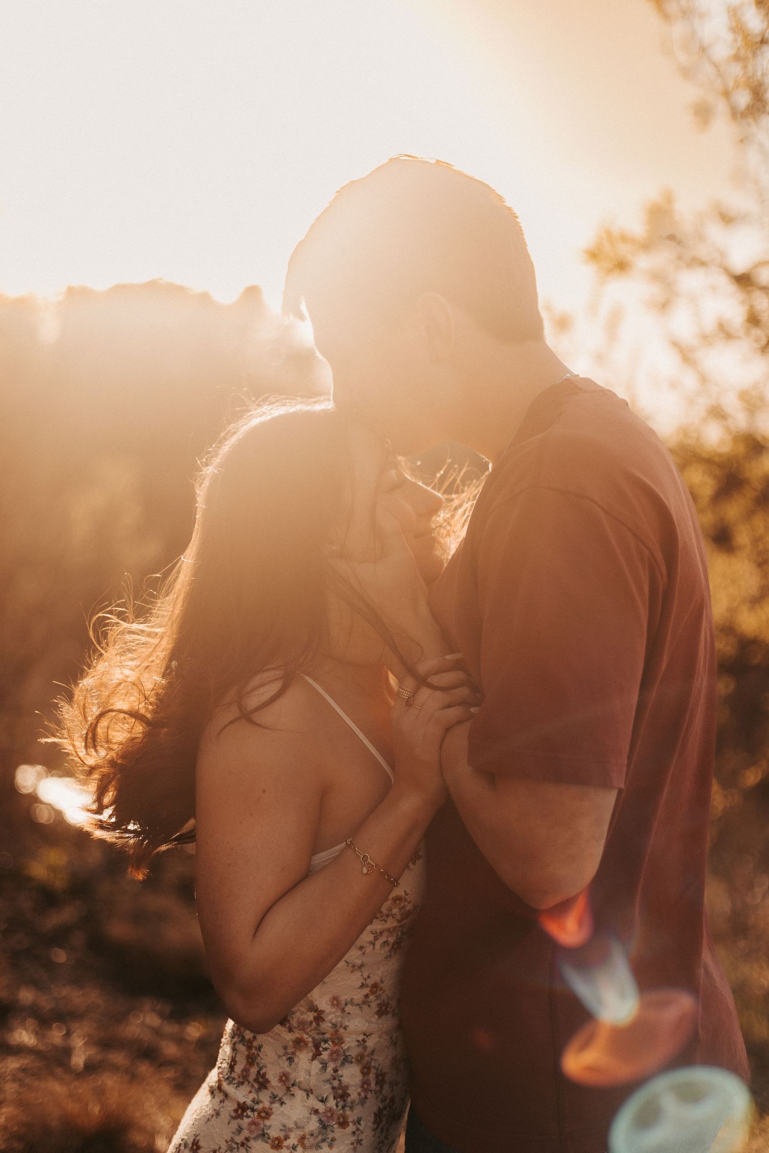 Couple sharing a romantic moment at golden hour sunset, bathed in warm glowing light outdoors.