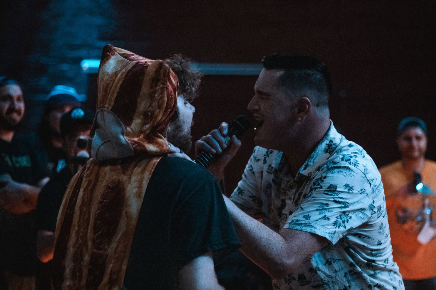 Two performers sharing a microphone on stage during an energetic live music concert performance.