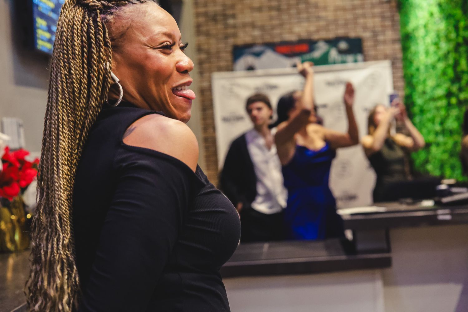 Woman with braids laughing at a lively party event inside Three Wide Brewing Co.