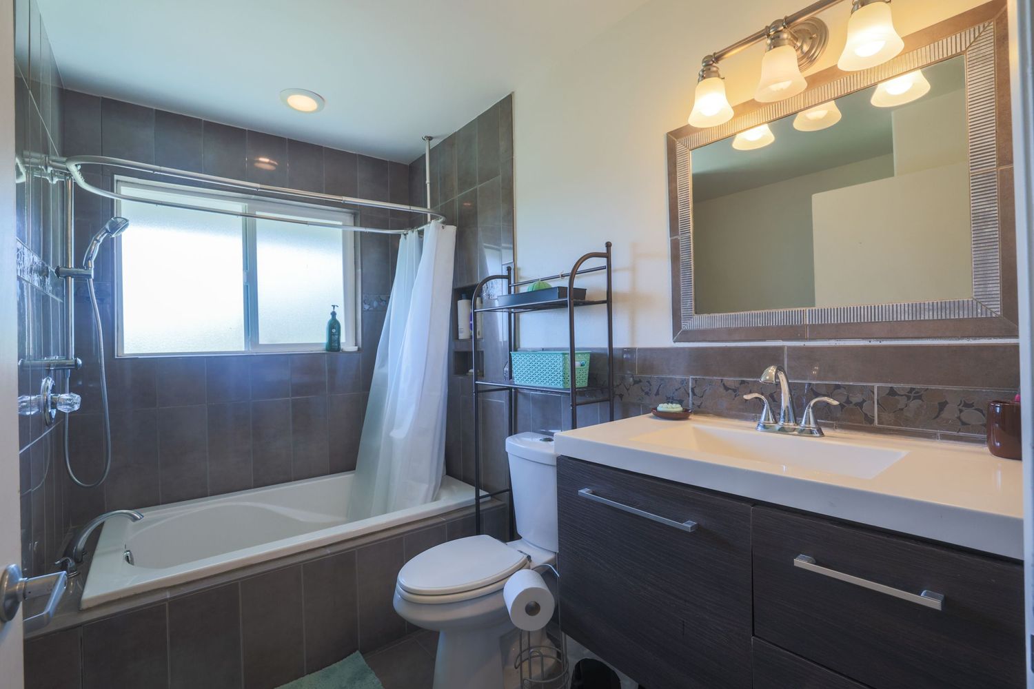 Modern bathroom interior with glass shower enclosure, vanity mirror, and warm lighting fixtures mounted above.