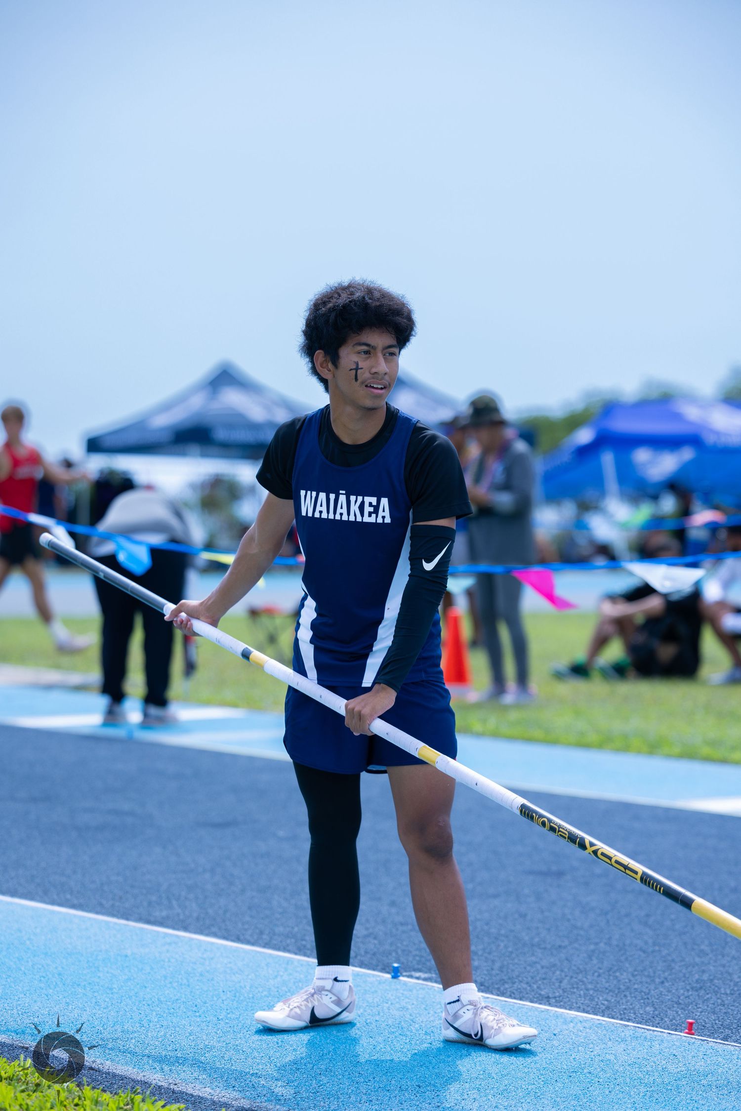 Track athlete in navy blue uniform prepares to throw a javelin during an outdoor competition.